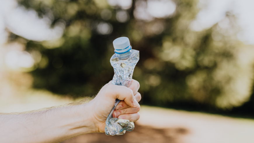 Une main serrant fermement une bouteille en plastique, symbolisant la lutte contre la pollution plastique.