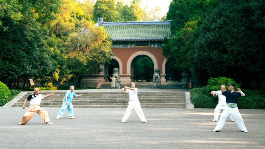 personnes pratiquant le Tai Chi Chaun devant un temple