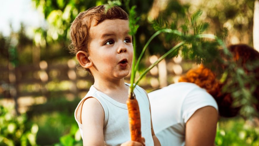 enfant heureux avec une carotte du jardin