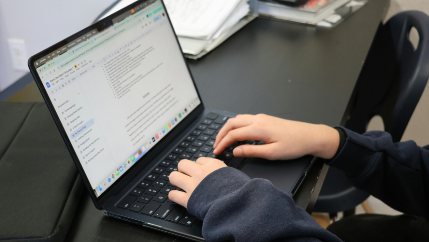 Fille assise devant un ordinateur en écrivant un e-mail.