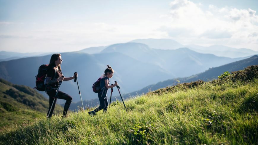 Deux filles marchant ensemble dans les montagnes, entourées d'une verdure luxuriante et immergées dans une nature préservée.