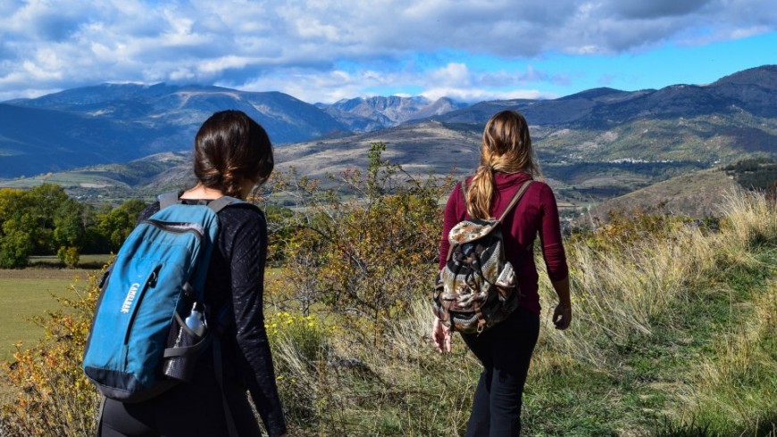 Deux filles faisant de la randonnée en montagne avec des sacs à dos légers, entourées de magnifiques paysages naturels.