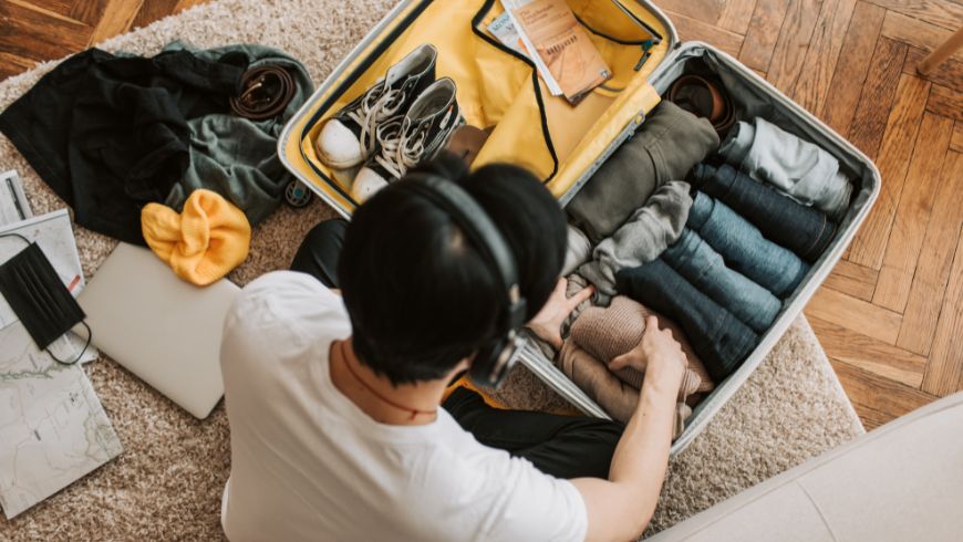Jeune homme emballant des vêtements polyvalents de couleur neutre, faciles à mélanger et à assortir.