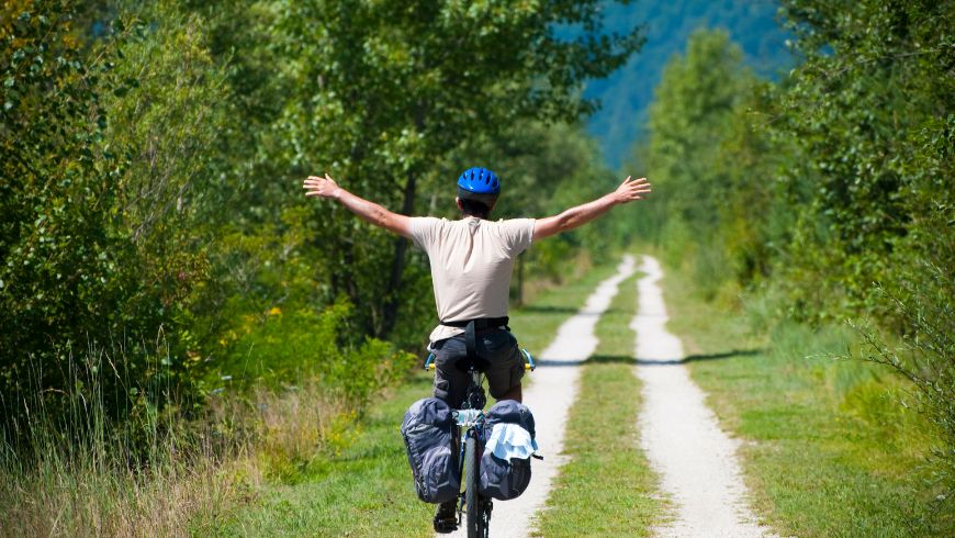 Voyageur à vélo le long d'une piste cyclable entourée de verdure
