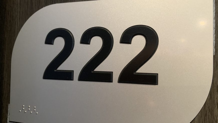 Porte de chambre d'hôtel avec numéro de chambre tactile et signalisation en braille