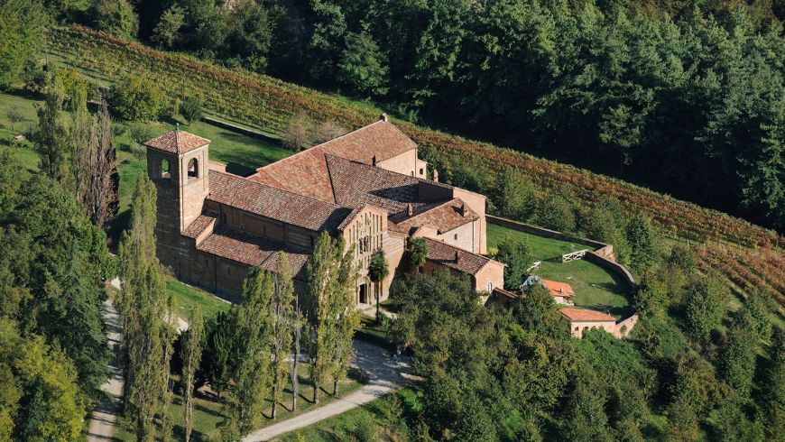 Vue aérienne de l'abbaye de Vezzolano, entourée de verdure et reliée aux sentiers de randonnée romans