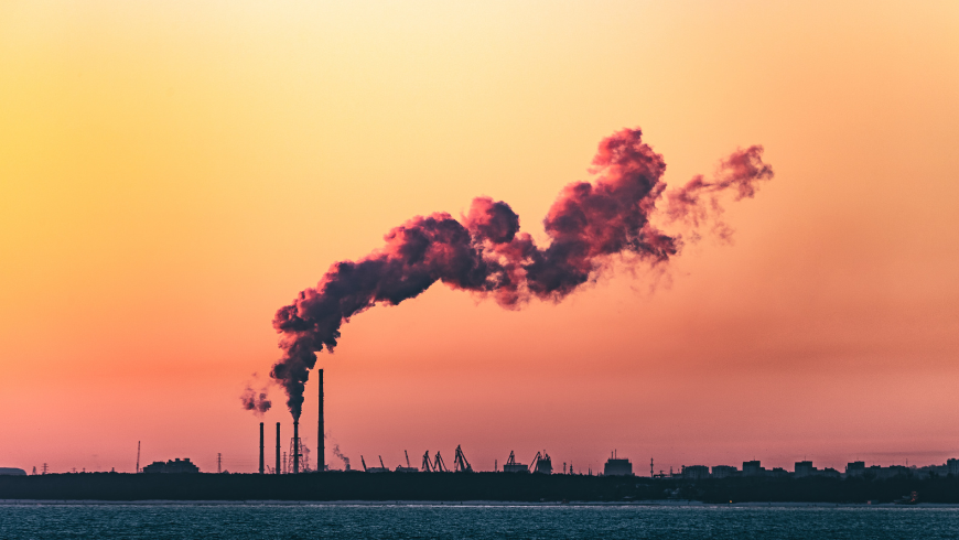 Paysage industriel au coucher du soleil avec des cheminées dégageant de la fumée noire